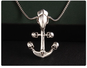 Macro detail of silver anchor pendant with skull design and polished square link chain
