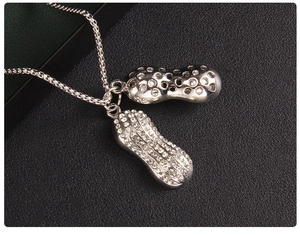 Détail macro du pendentif cacahuète argenté avec cristaux pavés et métal poli