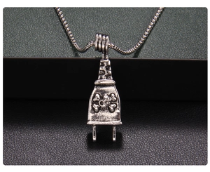 Macro shot of a punk-style skull plug pendant with textured chain on leather background