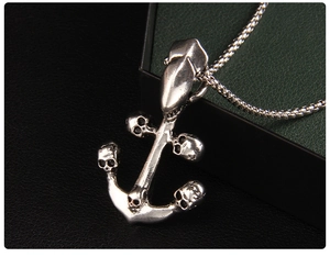 Detailed shot of silver anchor pendant with skull carvings on dark leather surface