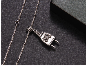 Close-up of punk style silver plug pendant with skull engraving on black leather