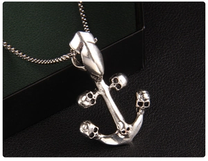 Detailed macro view of vintage silver anchor pendant with intricate skull carvings