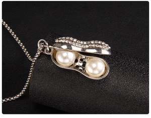 Détail macro du pendentif cacahuète argenté avec deux perles et diamants scintillants