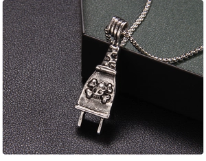 Macro detail of silver punk skull plug pendant on a metallic box chain necklace