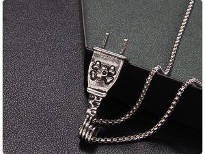 Macro shot of industrial punk plug necklace with silver skull and crossbones relief detail