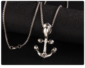 Macro shot of silver anchor pendant with skull details on a dark textured background