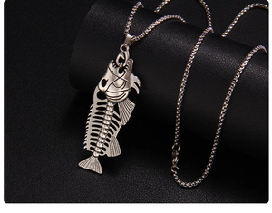 Macro shot of retro punk fish bone pendant with box chain on black leather background