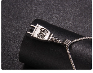 Macro detail of silver punk plug pendant featuring a skull and box chain texture