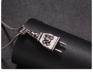 Close-up of punk style silver plug pendant with skull pattern on black leather