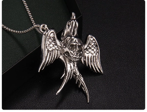 Detailed close-up of antique silver skull and bird wing pendant on black leather