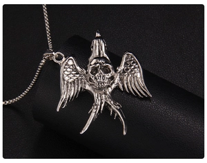 Macro detail of gothic flying bird and skull pendant with intricate silver metal texture