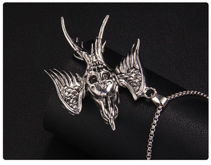 Macro shot of silver gothic skull pendant with feather wings and square box chain detail