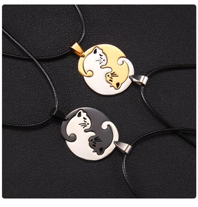 Détail macro de pendentifs chat yin-yang en acier inoxydable poli doré et noir
