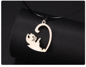 Gros plan d'un pendentif chat en acier argenté avec finition miroir sur support en cuir noir
