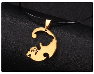 Vue détaillée d'un pendentif chat évidé doré suspendu à un cordon noir minimaliste