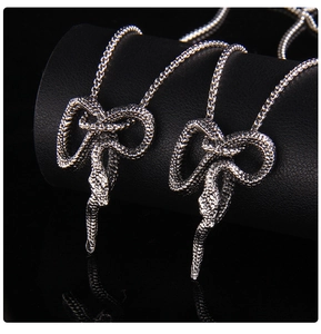 Close-up of vintage punk snake pendants with detailed scales on black leather stand