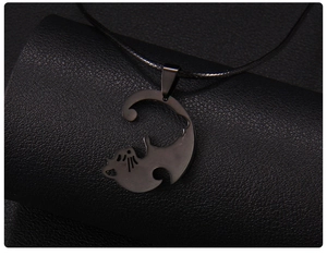 Gros plan du collier pendentif chat noir sur support texturé avec un style minimaliste