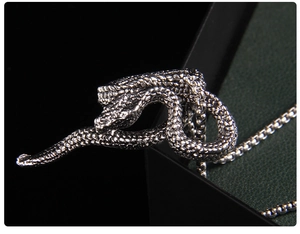 Macro shot of antique silver snake pendant with detailed scales on black jewelry box