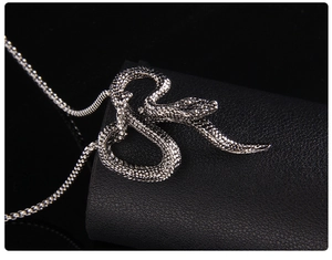 Detailed macro view of silver snake pendant with scale texture on black leather