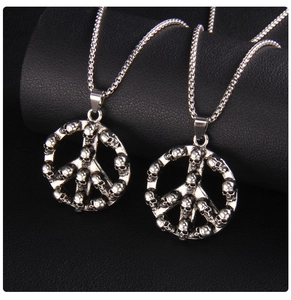 Close-up of vintage peace sign pendants made of tiny skulls on a metal box chain