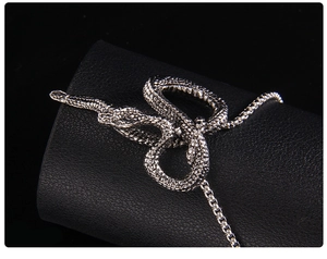 Macro detail of silver snake pendant with scale texture on a black display stand