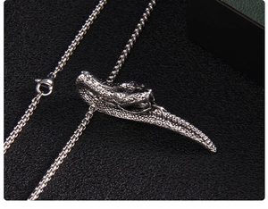 Vue détaillée du pendentif crâne de crocodile argenté avec textures d'écailles