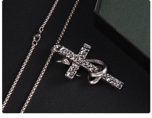 Close-up of gothic stainless steel cross necklace with snake and goat head details