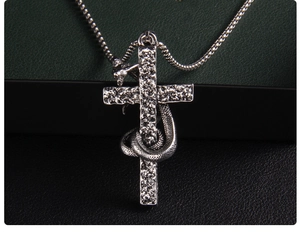 Macro detail of gothic snake wrapped around textured cross pendant in silver finish