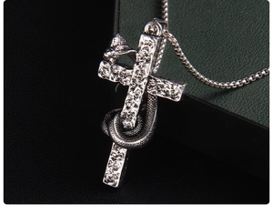 Detailed close-up of a silver cross pendant with an intricately carved coiled snake design