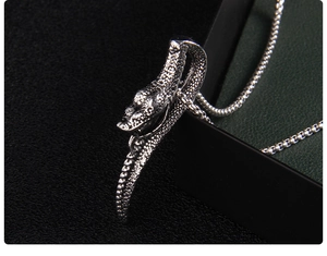 Vue détaillée du pendentif tête de serpent argenté style punk avec textures d'écailles