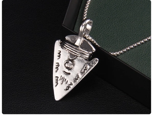 Close-up of vintage silver shield pendant with intricate Nordic viking engravings and ball chain