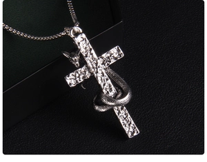 Close-up of silver punk cross pendant with wrapped snake and hammer texture finish