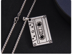 Détail du pendentif cassette vintage avec sa chaîne à mailles carrées en métal brossé
