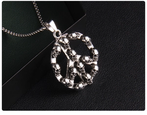 Macro shot of silver peace symbol pendant with miniature skulls and vintage finish