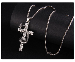 Detail of gothic stainless steel cross pendant with coiled snake on dark leather