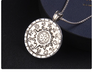 Macro shot of silver sun compass pendant featuring detailed twelve zodiac constellations