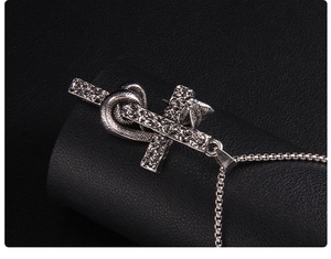 Macro shot of silver punk snake coiled around a stone-textured cross pendant necklace
