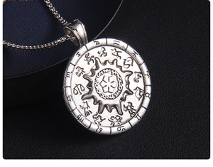 Macro detail of silver sun compass zodiac pendant with vintage embossed texture
