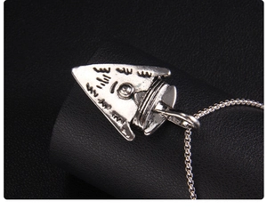 Macro shot of silver arrow pendant with vintage texture and polished stainless steel chain