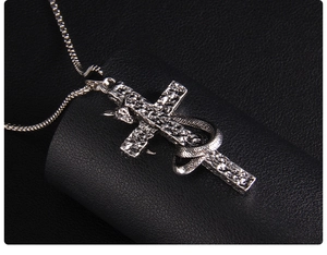 Detailed close-up of punk style snake wrapped cross pendant on leather surface