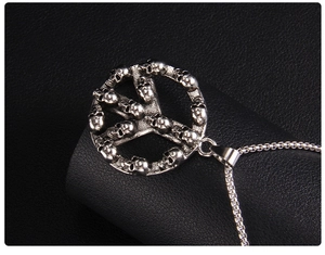 Macro shot of silver peace sign pendant made of skulls on black leather background