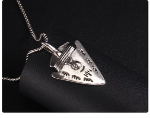 Macro view of vintage silver arrowhead pendant with engraved symbolic details and chain