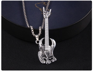 Macro view of rock-style guitar pendant with skull relief and hand gesture on box chain