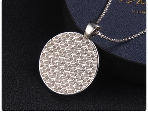 Macro shot of silver compass necklace back with geometric cube texture and box chain