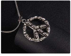 Detail shot of vintage skull peace sign pendant on black leather background
