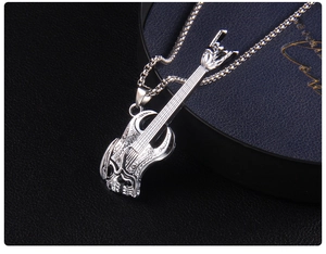 Macro shot of a silver guitar pendant featuring skull relief and rock hand gesture headstock