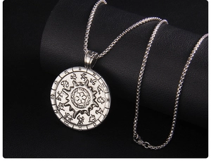 Macro shot of stainless steel sun compass necklace with zodiac symbols on black leather