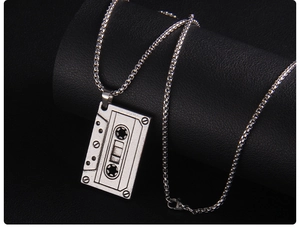 Détail d'un pendentif cassette rétro avec chaîne box argentée sur fond en cuir noir