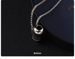 Vue du bas du pendentif biberon et de la chaîne carrée argentée sur boîte