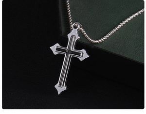 Vue macro d'un pendentif croix argenté avec émail noir sur une fine chaîne à billes